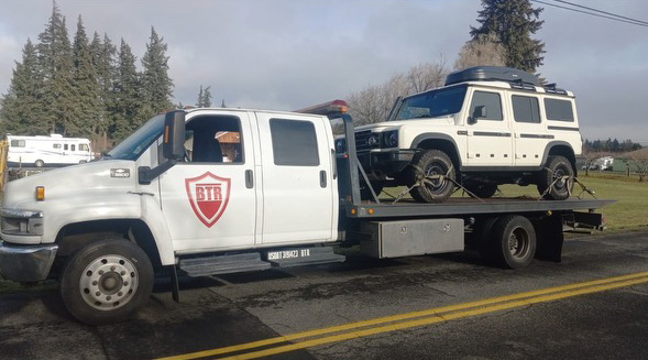 Flatbed towing a Land Rover Defender